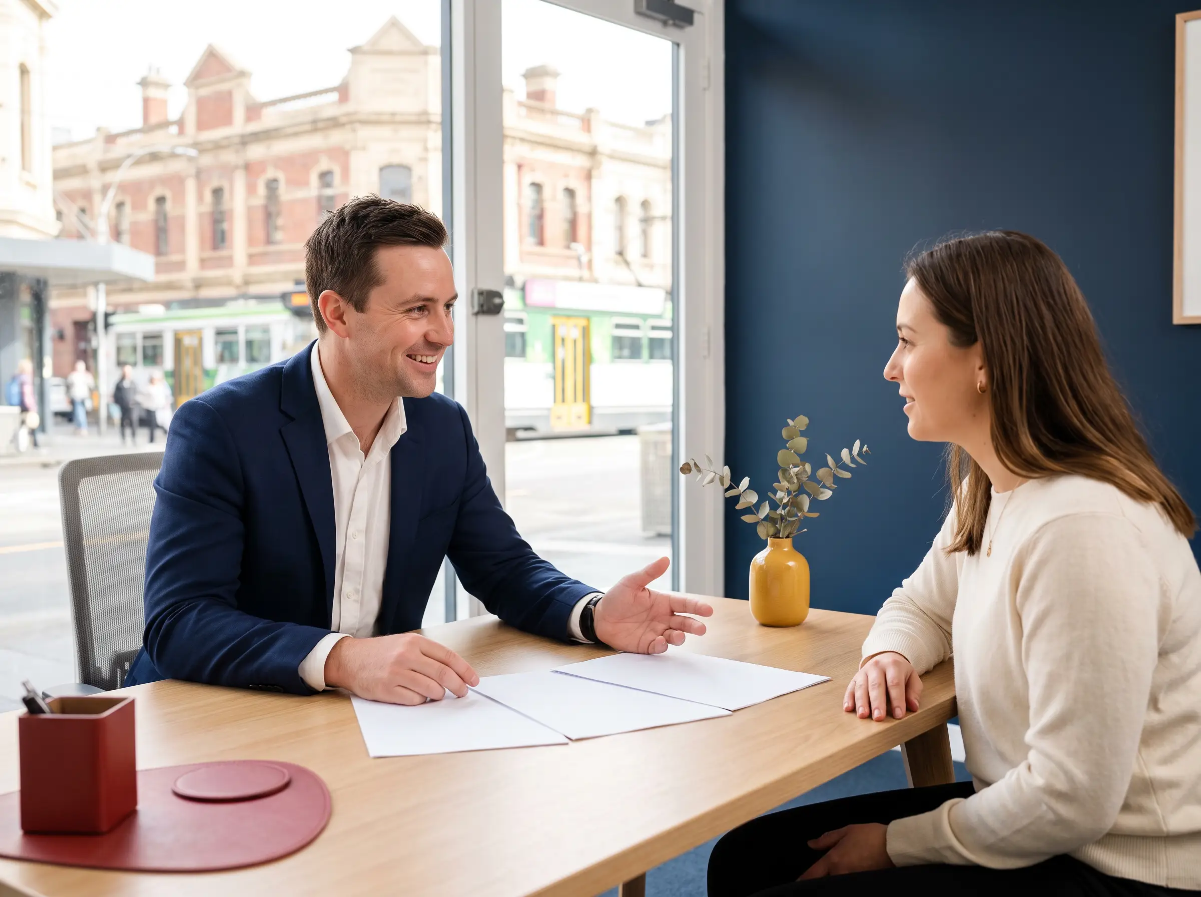 A financial adviser talking with a client across a desk in a Melbourne office