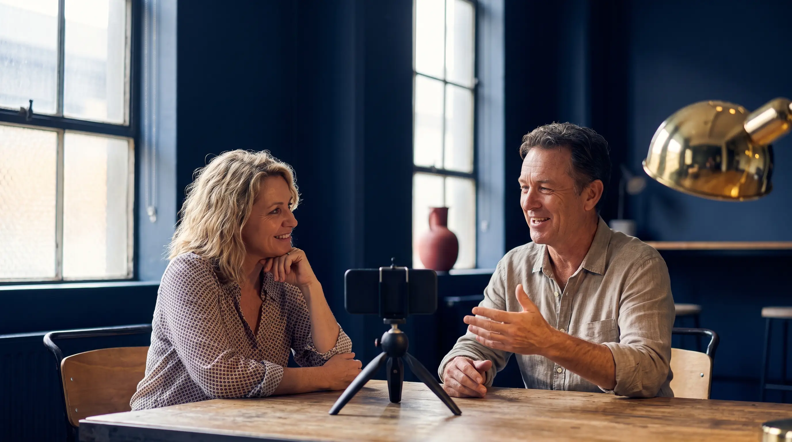 Small business owner being interviewed by a colleague while a phone records the conversation